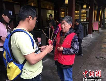灵隐寺的义工在发放三支清香。 杨韵仪 摄